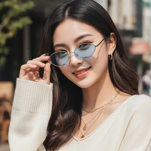 Vintage oval metal sunglasses with light blue lenses and gold frames on fashion model