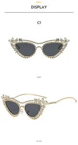 Detail of luxury gold cat-eye sunglasses with rhinestone floral accents and dark lenses
