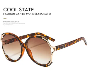 Détail de lunettes de soleil écaillées avec décor en métal doré et verres dégradés marron