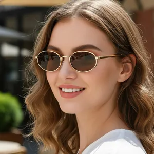 Retro oval sunglasses with gold metal frames and brown lenses worn by a model in the street