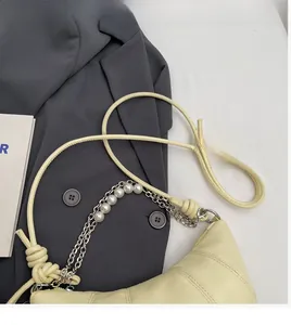Detail of cream quilted crossbody bag featuring elegant pearl chain and soft leather strap