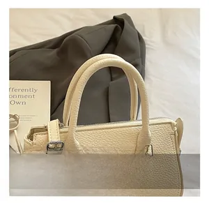 Detail of cream leather handbag showing litchi grain texture and silver hardware