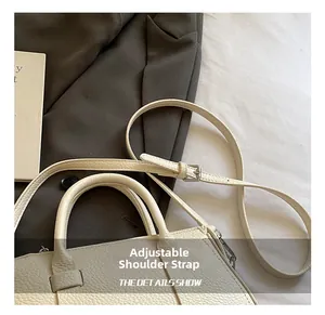 Detail of adjustable shoulder strap and silver metal buckle on beige lychee leather bag