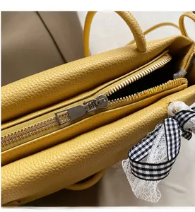 Detail einer leuchtend gelben Baguette-Tasche mit silbernem Reißverschluss und Schleife