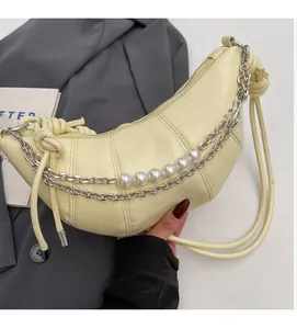 Detail of pale yellow crescent bag with double metal chains and large pearl accents