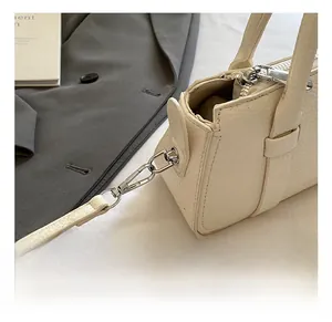 Close-up of detachable silver metal hook and pebble grain leather on creamy white bag
