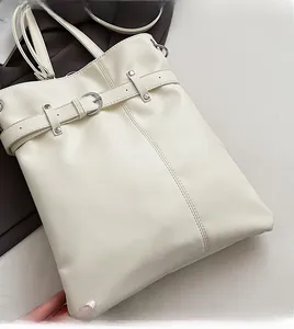 Close-up of cream white bucket bag with decorative buckles and vertical double stitching