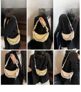 Detail view of crescent shoulder bag featuring pearl chains and knotted handle in beige color