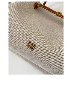 Detalle del logotipo de metal PAN TOR en bolso de lona beige y cuero marrón
