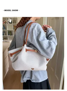 Bolso tote grande de tela gris con correas de cuero marrón mostrado por una modelo