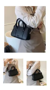 Detail of black lychee grain leather tote bag with gold logo and adjustable shoulder strap