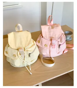 Detail of mini canvas backpacks in yellow and pink showing flap and buckle design