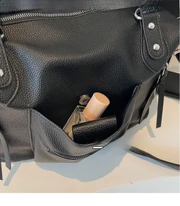 Dettaglio della borsa tote in pelle martellata nera con tasca laterale e fibbia magnetica