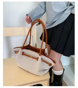 Detalle de bolso de lona con asas de cuero marrón y hebilla dorada en silla de madera