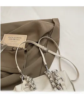 Detail of cream leather handbag featuring silver chain handle and adjustable strap