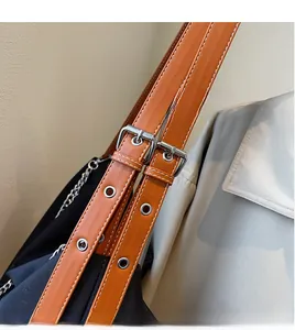 Detail view of adjustable leather shoulder strap with silver buckle on black tote bag