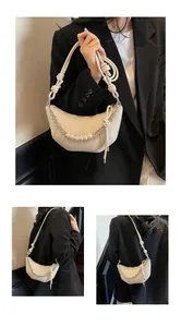 Detail of beige croissant bag with pearl chain and pleated design on black blazer