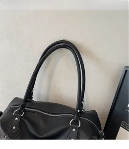 Dettaglio della borsa tote in pelle martellata nera con zip argento e rivetti rinforzati