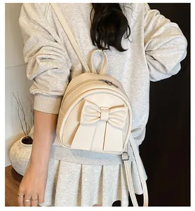 Close-up of a cream PU leather mini backpack featuring a stylish large bow detail
