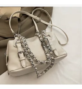 Detail of cream crossbody bag with silver chain strap and leather buckle decor