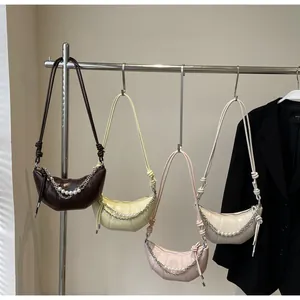 Detail of croissant-shaped shoulder bags featuring pearl chains and knotted straps
