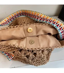 Dettaglio della chiusura magnetica e della tracolla jacquard colorata di una borsa in paglia