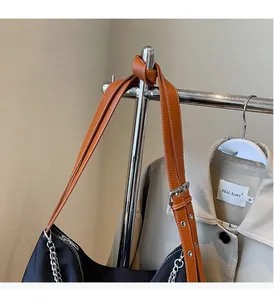 Detail of adjustable leather strap with metal eyelets on a black nylon tote bag