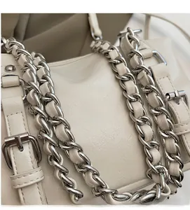 Close-up of cream leather texture and silver chain strap on a stylish crossbody bag