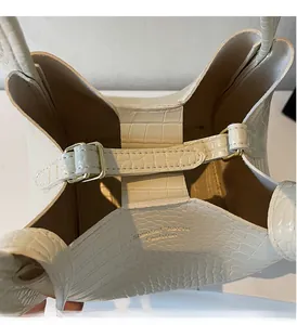 Detailed close-up of white crocodile pattern bucket bag showing gold metal buckle and texture