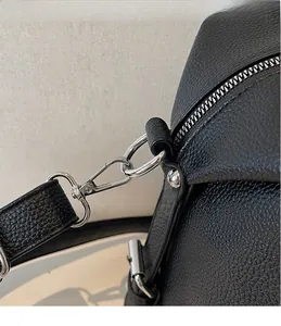 Dettaglio dei ganci in metallo argento e della tracolla su borsa in pelle nera