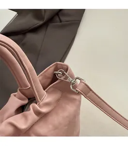 Detail of silver metal hook and pleated leather texture on a soft pink handbag