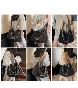 Detail of black tote bag with silver chain straps and adjustable brown leather strap