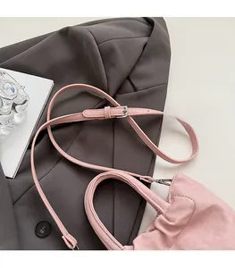 Close-up of pink ruched handbag with adjustable shoulder strap on grey blazer