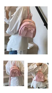 Detail of a pink mini backpack featuring a large bow and silver zipper on the strap