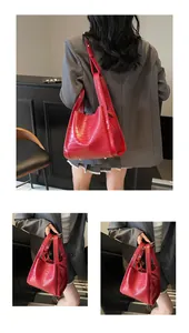 Détails d'un sac seau rouge à motif crocodile avec pieds en métal et bandoulière