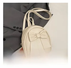 Detail showing the cream mini backpack with large bow decoration and smooth PU leather