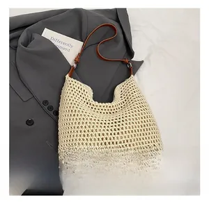 Detail of hollow-out cream woven beach bag with brown leather strap and metal buckle
