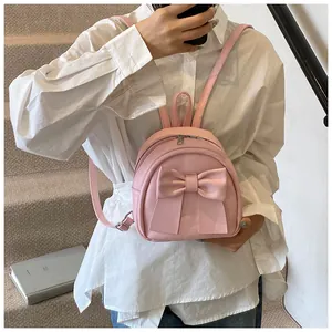 Detail of pink mini backpack with oversized bow decoration and dual metal zippers