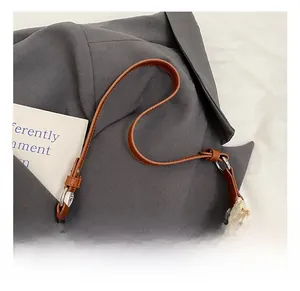 Close-up of brown leather strap and silver ring on woven straw shoulder bag