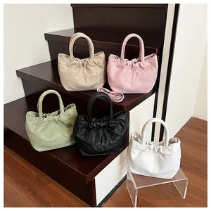 Close-up of pleated tote bags in five colors on wooden steps for hand or crossbody use