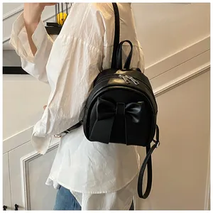 Rear view of a model wearing the mini black leather backpack with a decorative bow