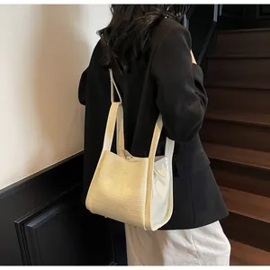 Detail view of cream white croc-effect leather bucket bag worn by model on shoulder