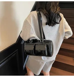 Detail of black patent leather shoulder bag featuring dual front pockets and silver buckle