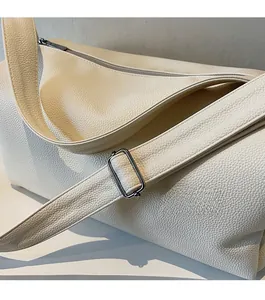 Close-up of adjustable wide shoulder strap with silver buckle on lychee leather bag