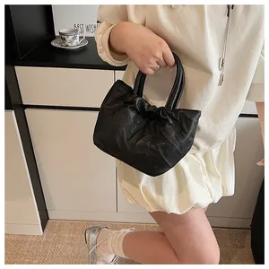 Close-up of black pleated bucket bag with soft leather texture and stylish round handle