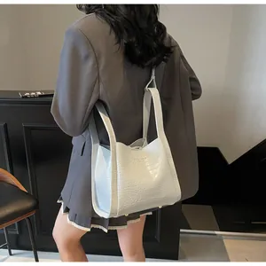Détail du sac cabas blanc à motif crocodile avec bandoulière longue porté à l'épaule