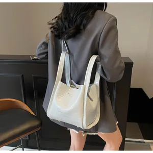 Detailed view of crocodile pattern bucket bag with metal feet and brand lettering