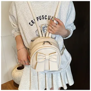 Detail of a chic cream mini backpack with a large bow on smooth leather for women