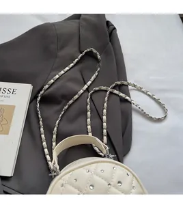 Detail of cream quilted mini backpack with rhinestone accents and metal chain strap