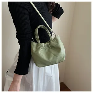 Detail of light green drawstring bucket bag with soft pleated texture and silver hardware